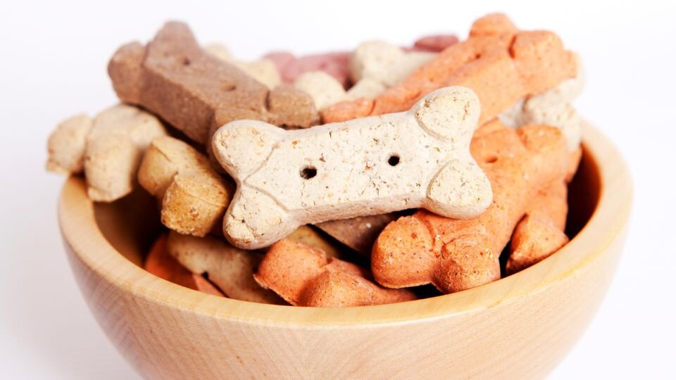 Zdjęcie przedstawia drewnianą miskę pełną różnych przekąsek dla psa